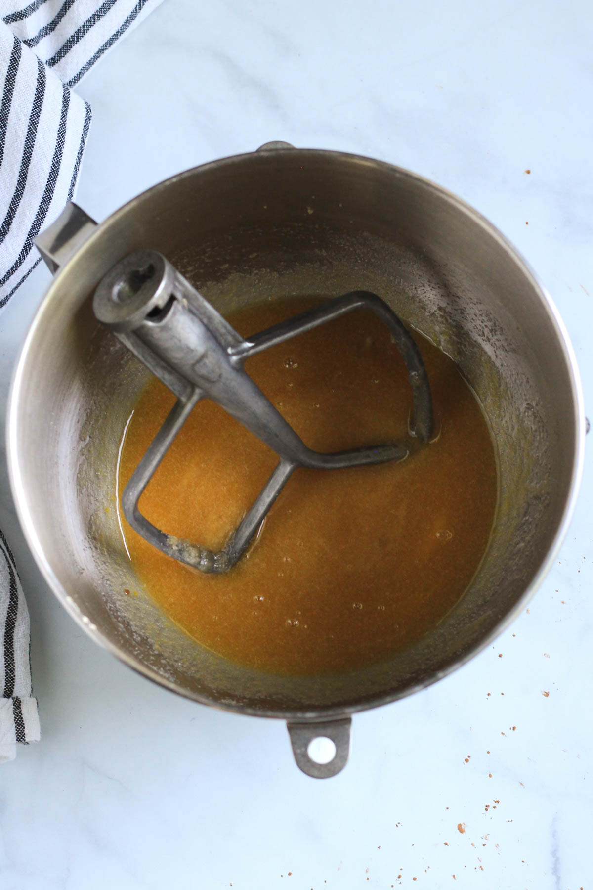 A silver bowl with the paddle attachment with creamed sugar and oil with egg, vanilla, and coffee.