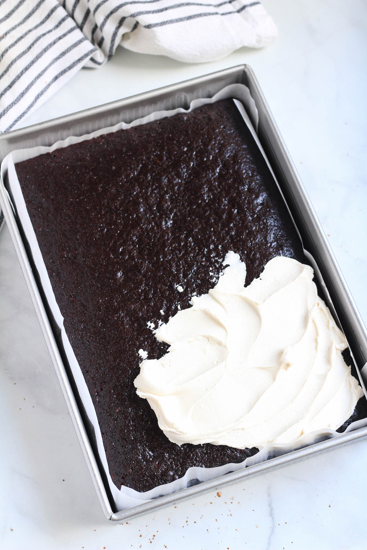 A dairy-free chocolate cake being frosted with coffee buttercream.