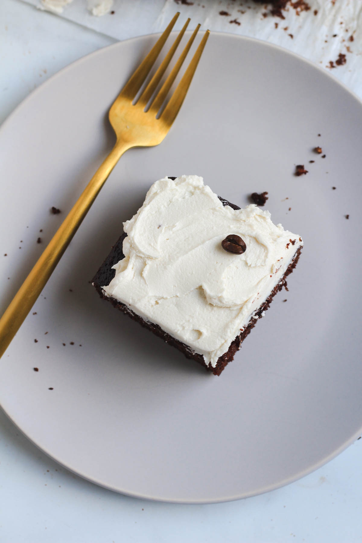 Coffee buttercream frosted chocolate cake with a gold fork on a white plate.