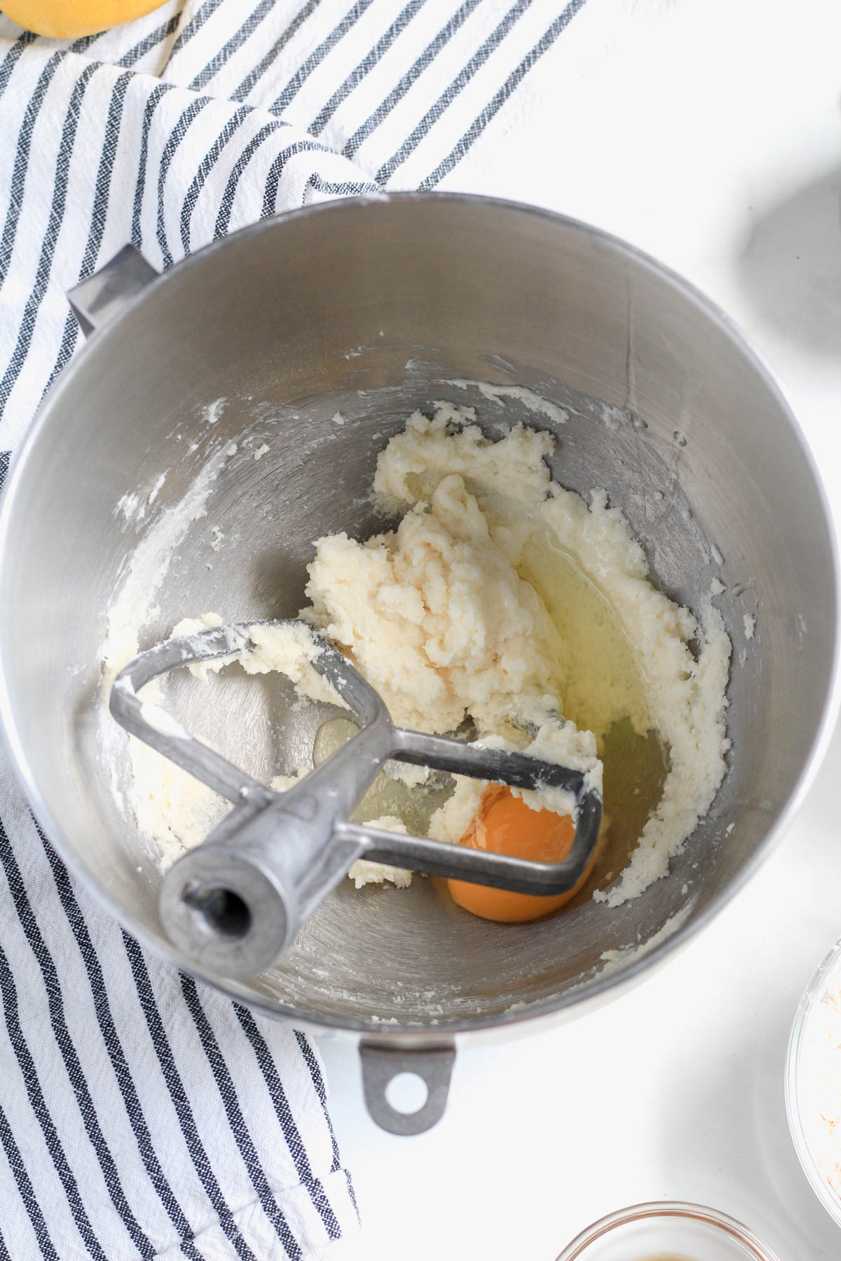 Creamed plant-based butter and sugar with an egg before mixing with a paddle attachment in the bowl to the left.