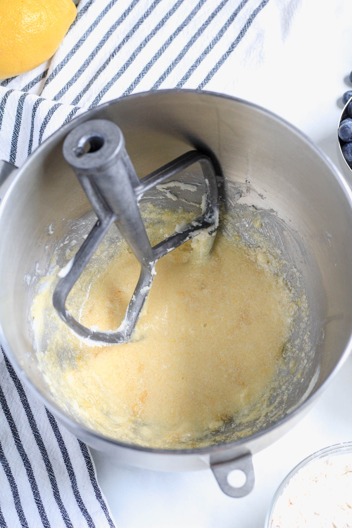 Lemon blueberry coffee cake batter after mixing the egg in with a paddle attachment to the top left of the bowl.