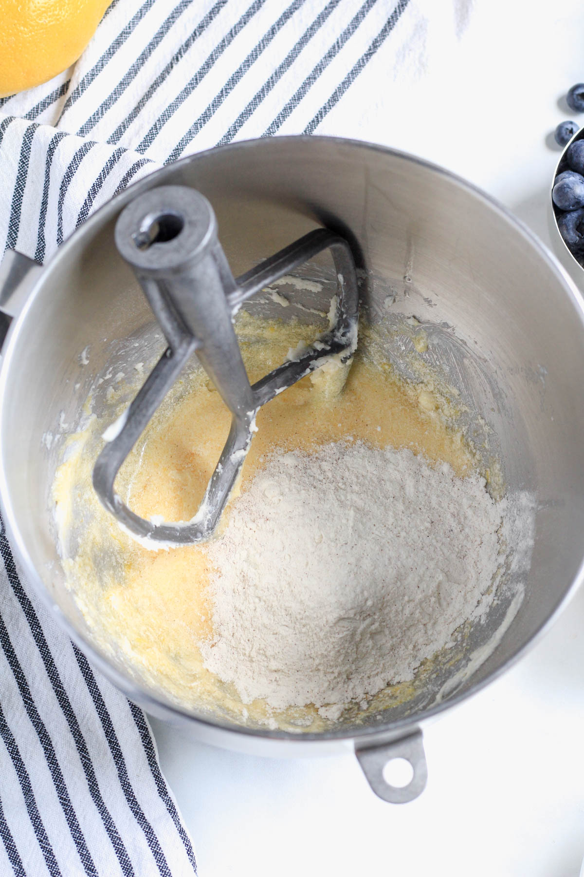 Flour added to the mixing bowl before mixing with a paddle attachment to the top left of the bowl.
