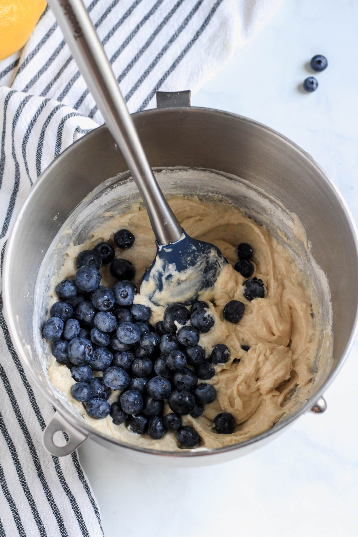 Blueberries on top of the coffee cake batter with a spatula in the mixing bowl.