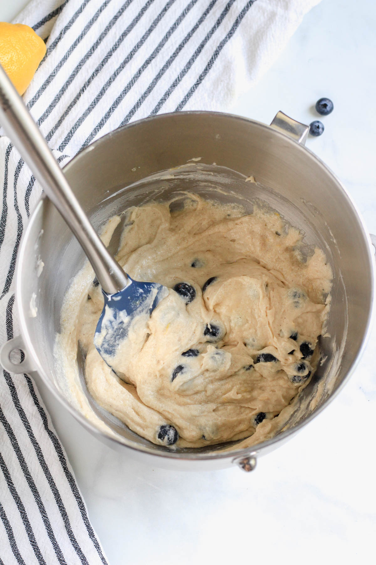 Lemon blueberry coffee cake after mixing the blueberries with a spatula on the left side of the mixing bowl.