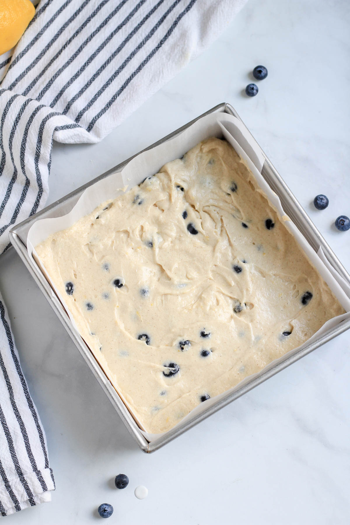 A square baking pan filled with lemon blueberry coffee cake batter before topping and baking.