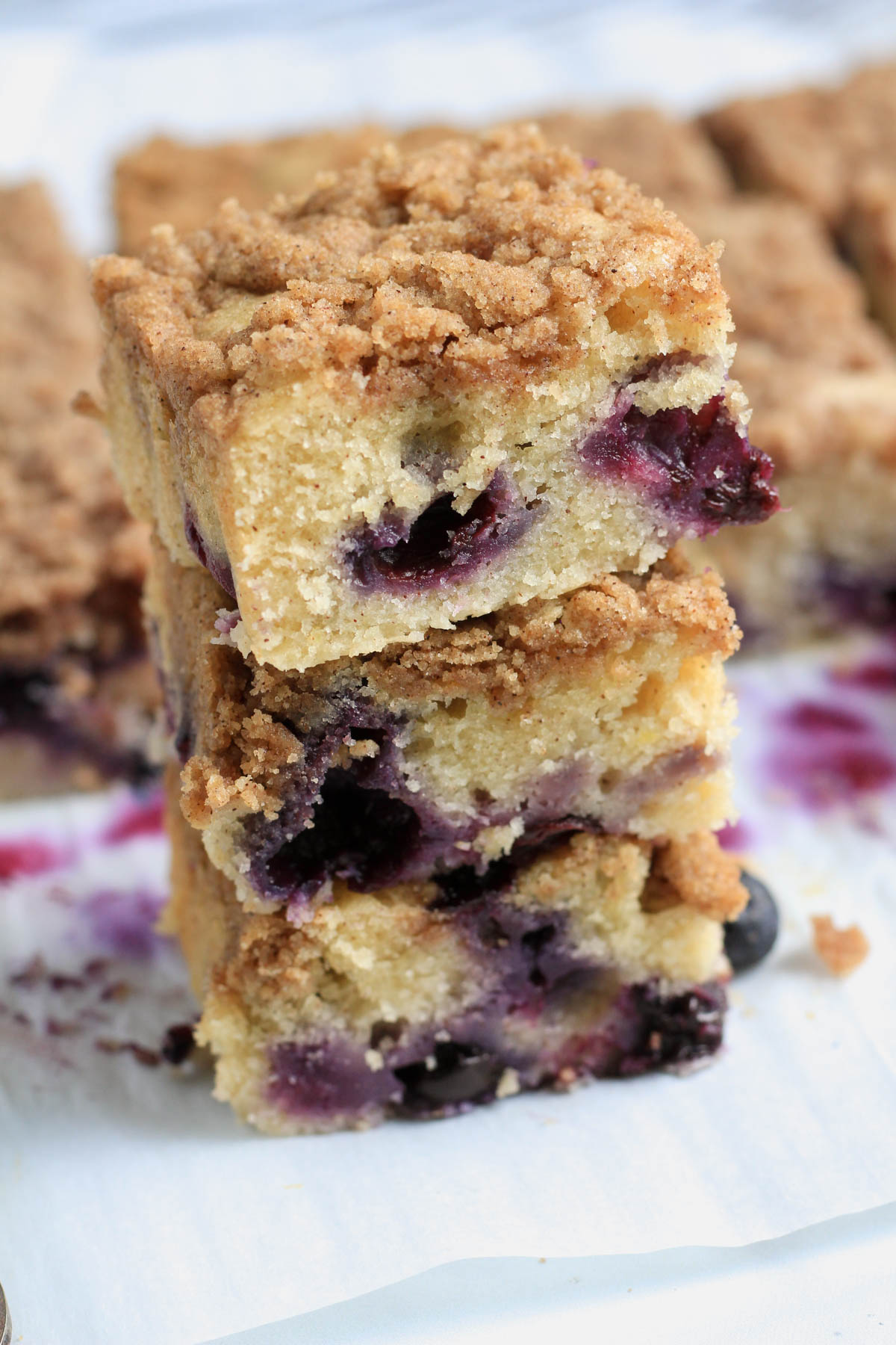 A stack of three squares of coffee cake on a piece of parchment paper.
