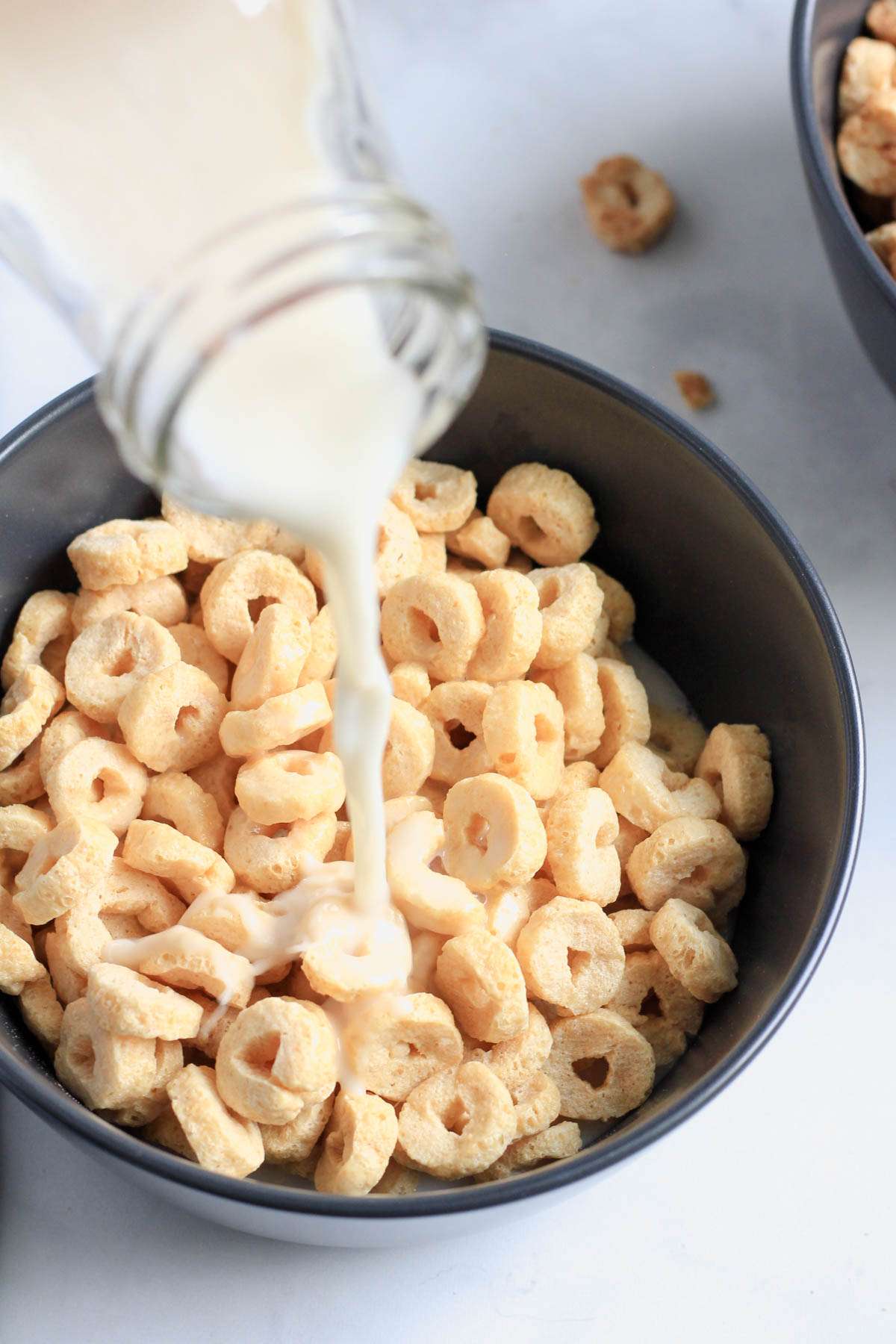 Non-dairy milk pouring over a bowl of frosted cereal.