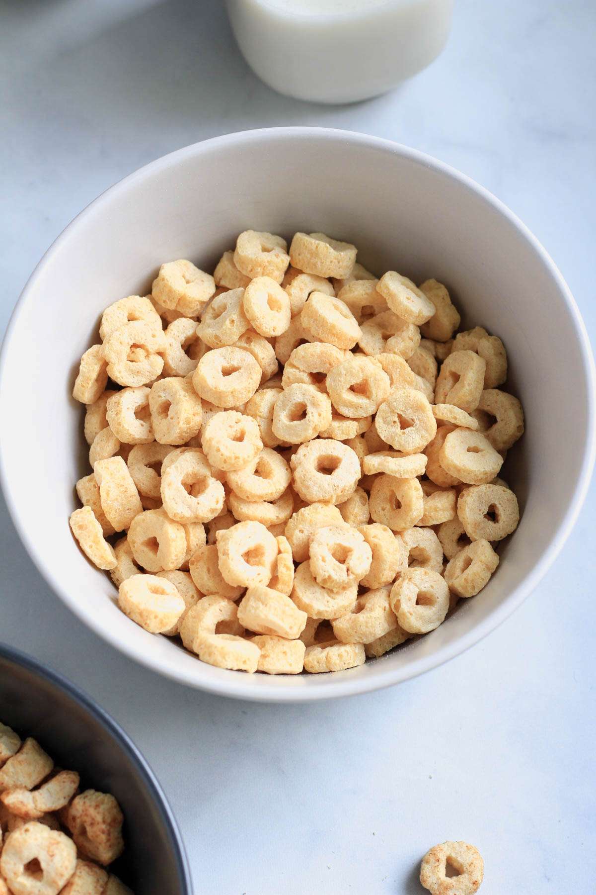 A white bowl with honey cereal and a small bottle of non-dairy milk above the bowl.