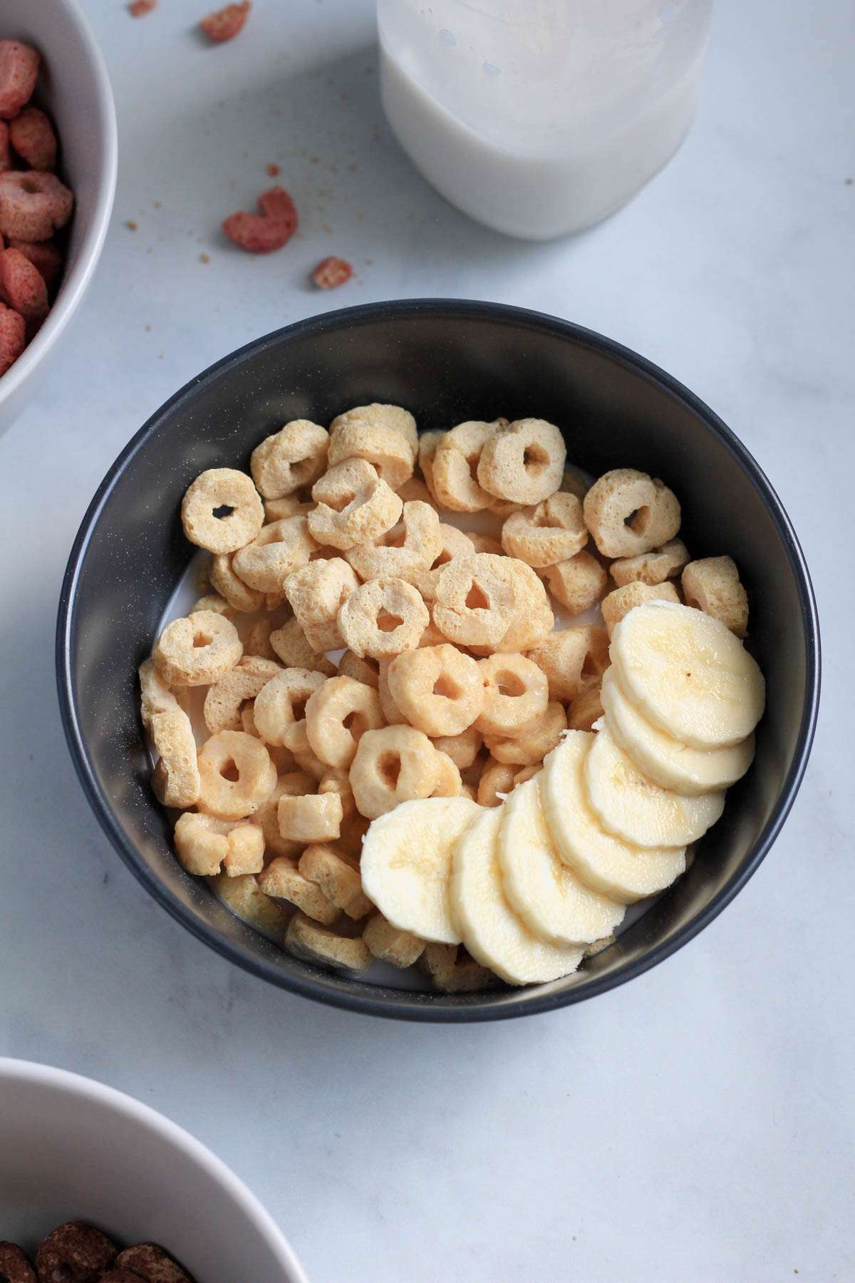 A blue bowl of unsweetened cereal topped with slices of banana.