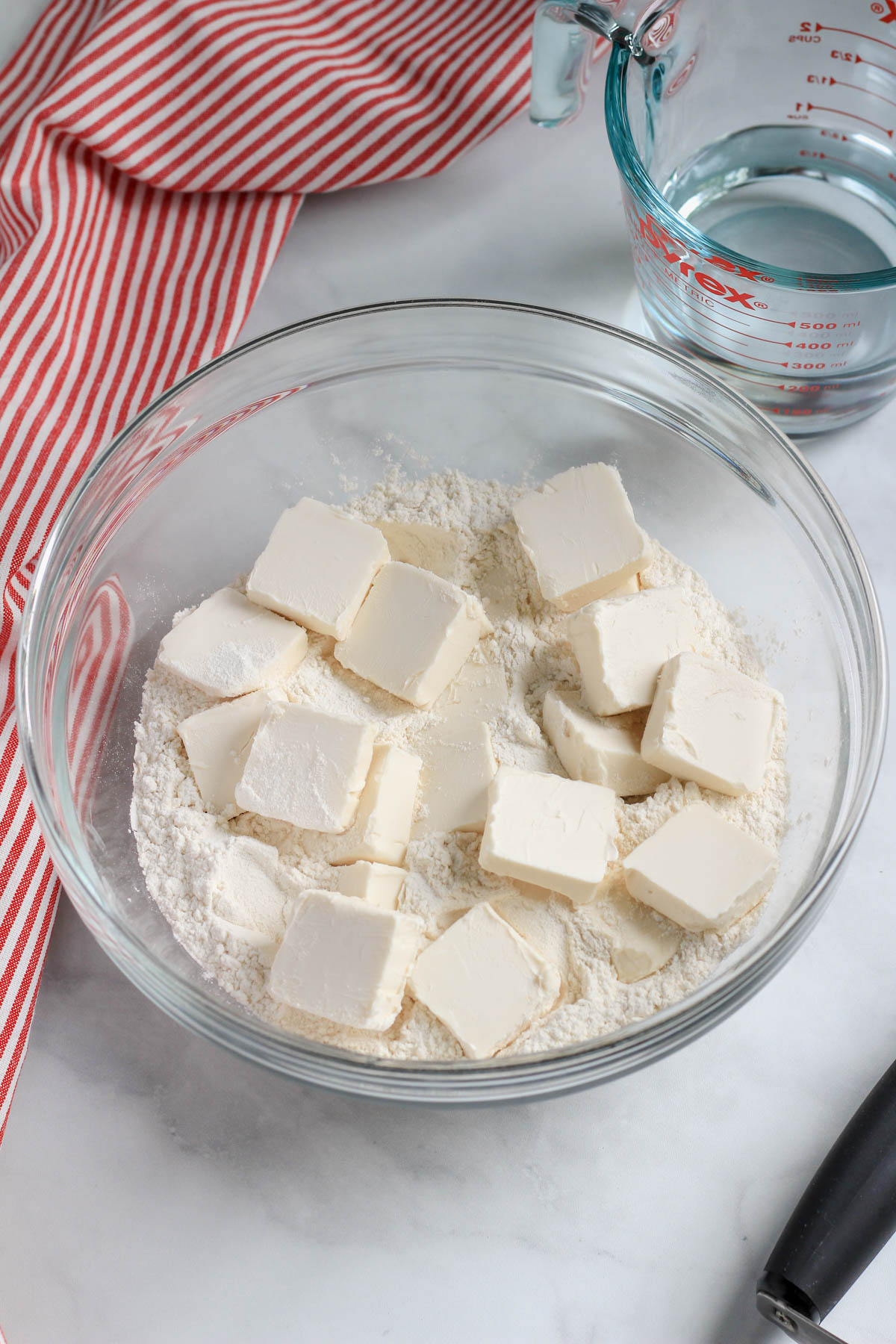 A glass bowl with a flour mixture topped with vegan butter.