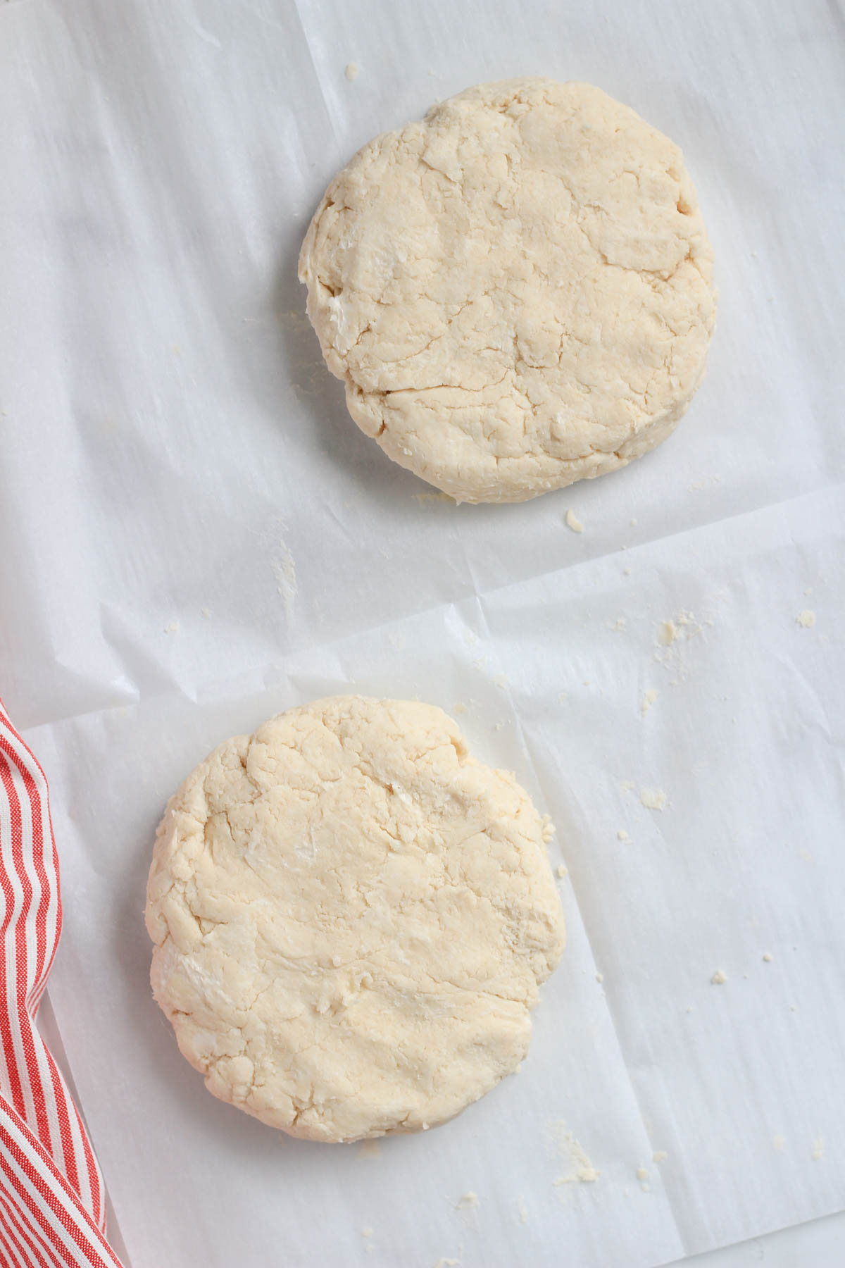 Two round disks of vegan all butter pie crust on a white parchment paper.