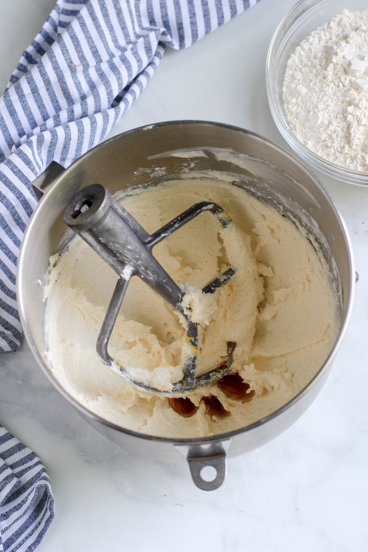 Creamed plant-butter and sugars with vanilla and lemon juice in a silver bowl with paddle attachment.