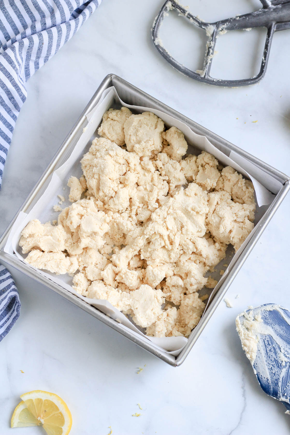 Lemon shortbread cookie dough on a white counter with a slice of lemon in the bottom left.