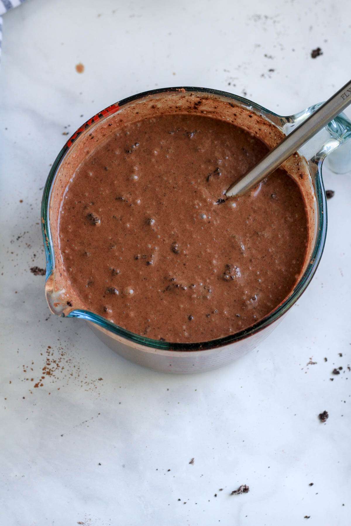 A large liquid measuring cup with a small whisk and Oreo fudgesicle filling.