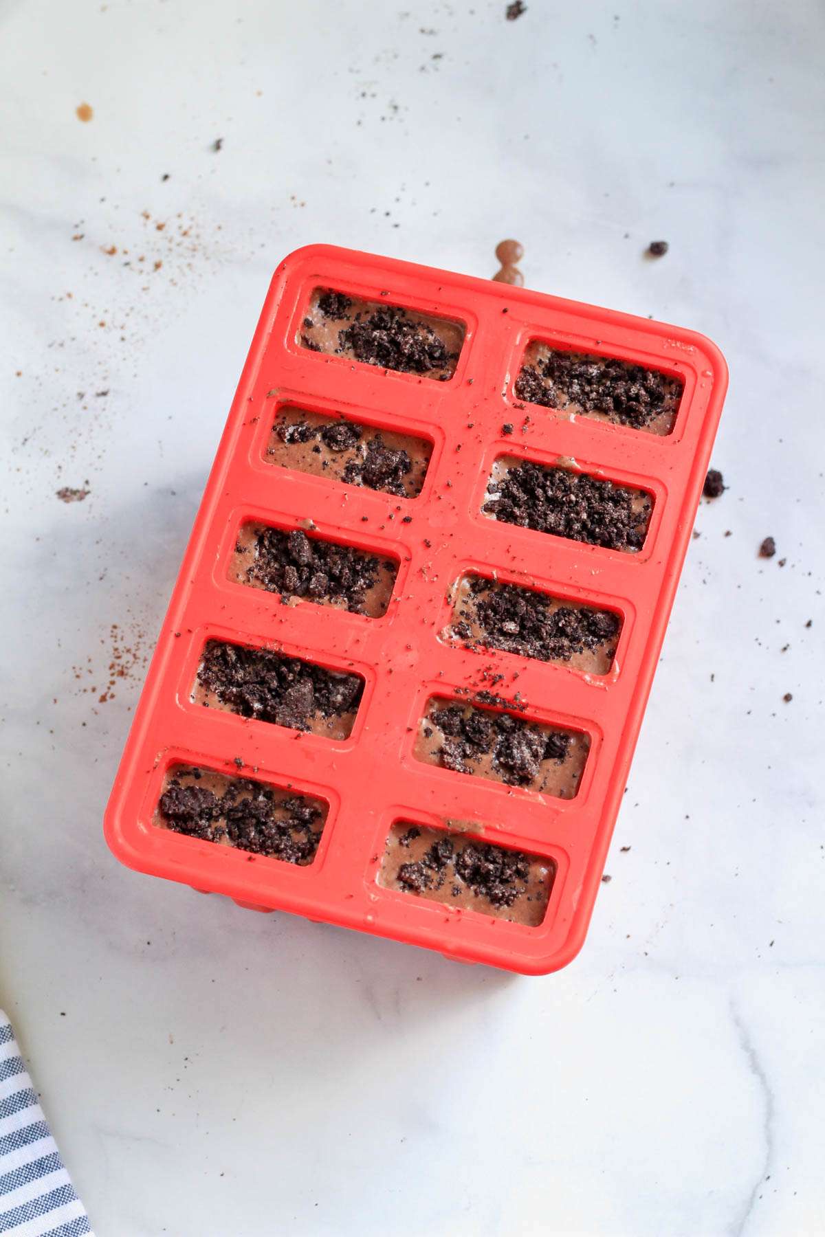 A popsicle mold filled with Oreo fudgsicle filling and topped with Oreo crumbs.