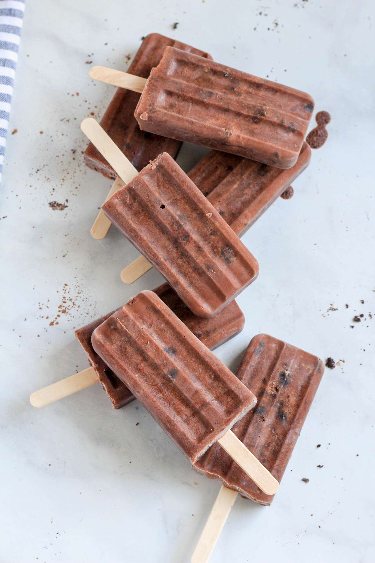 A white counter with chocolate Oreo fudgesicles scattered about.