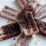 A close up of a chocolate Oreo fudgesicle on top of a pile of vegan Oreo fudgesicles.