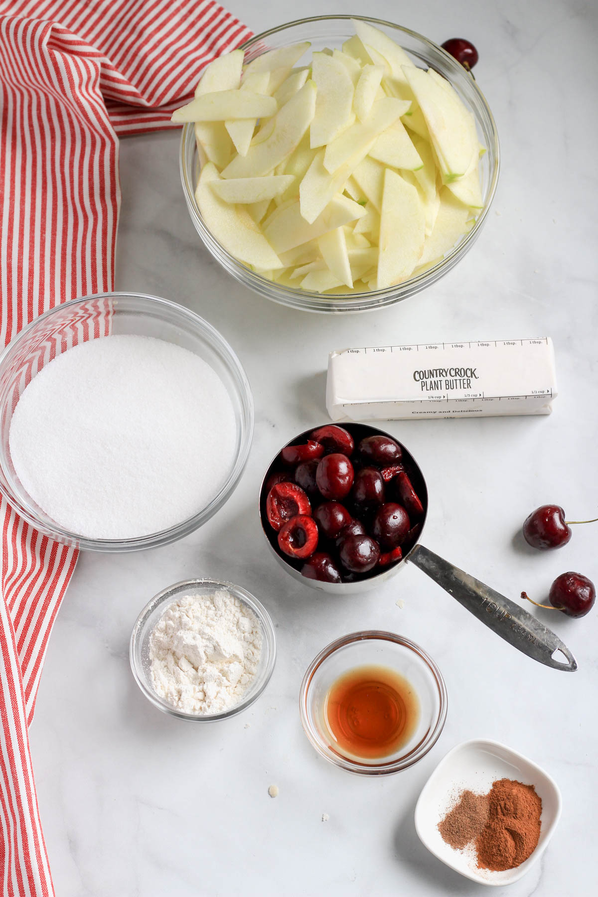 Ingredients for vegan apple cherry pie on a white counter.