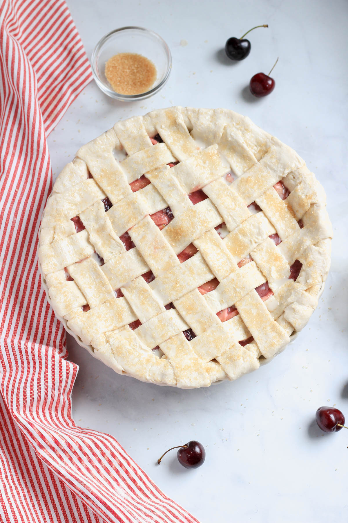 A vegan cherry apple pie topped with an oat milk and sugar topping.