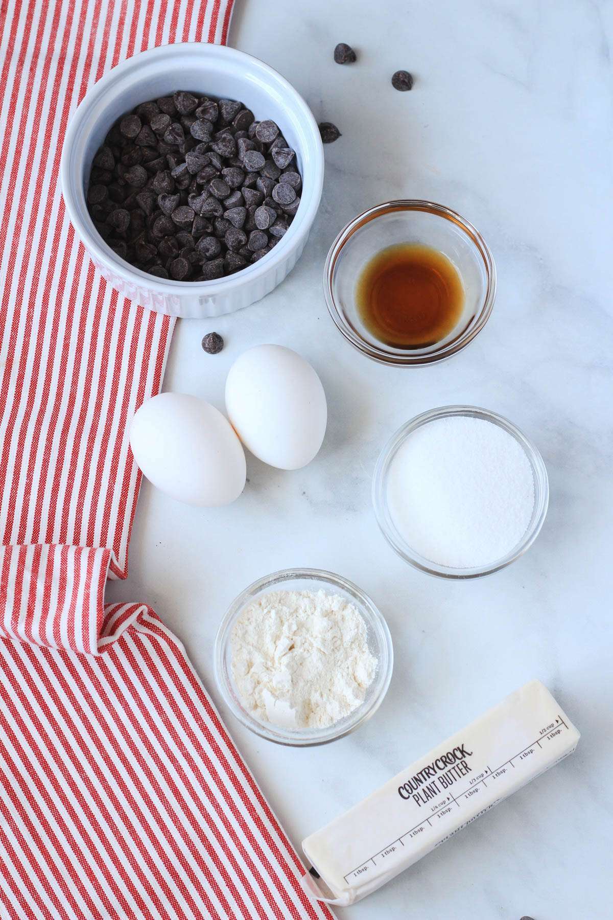Ingredients for chocolate lava cakes on a white counter with a red and white striped towel to the left.