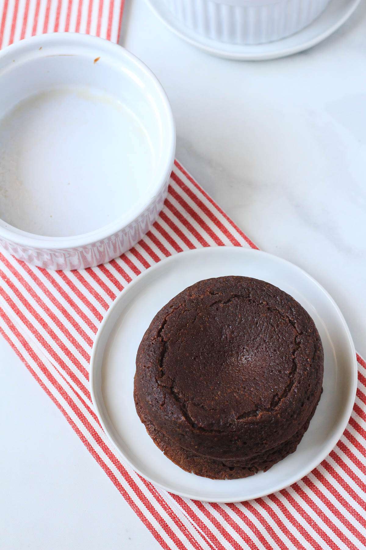 A white plate with a chocolate lava cake after being flipped out of the ramekin.