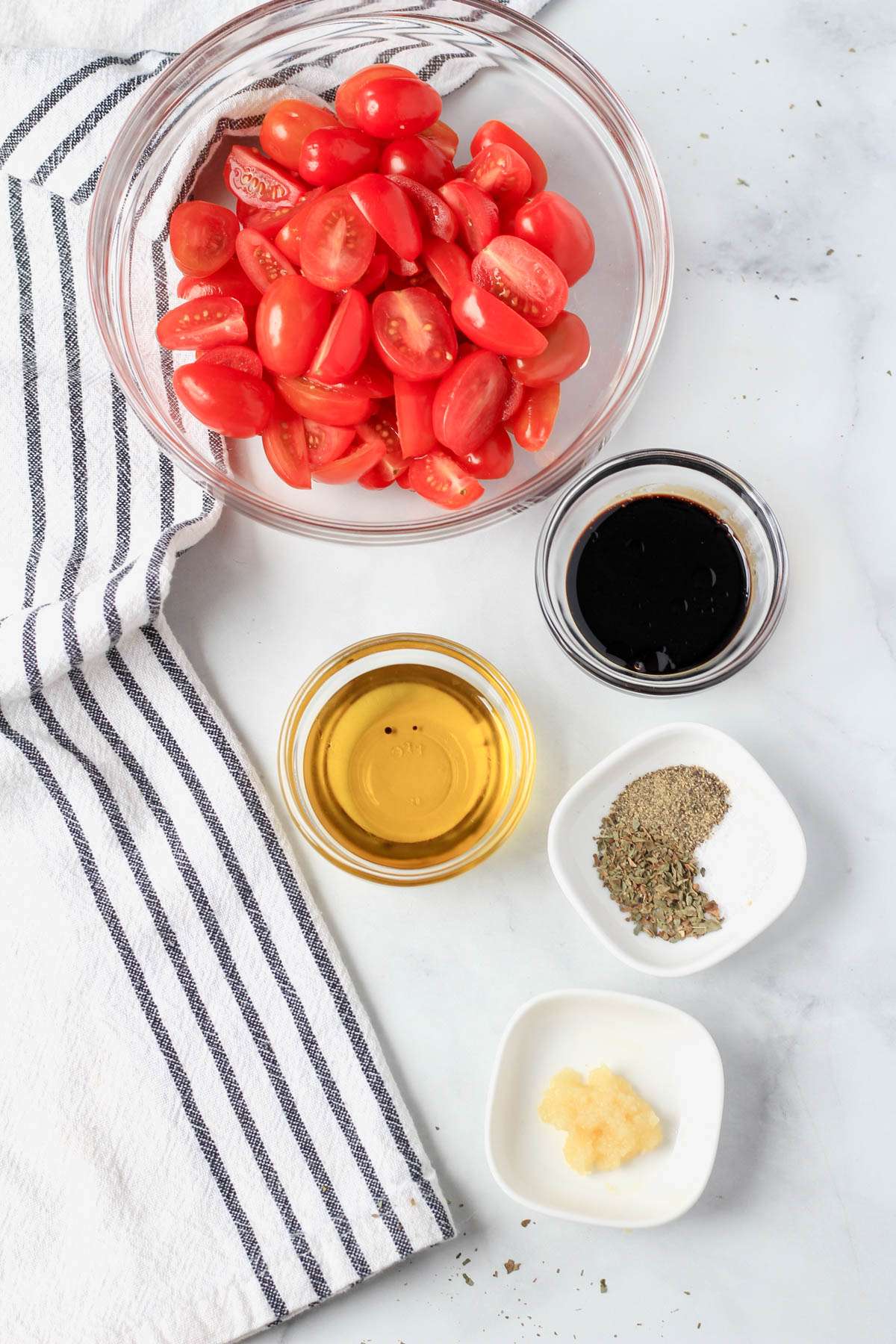 Ingredients for marinated tomatoes on a white counter.