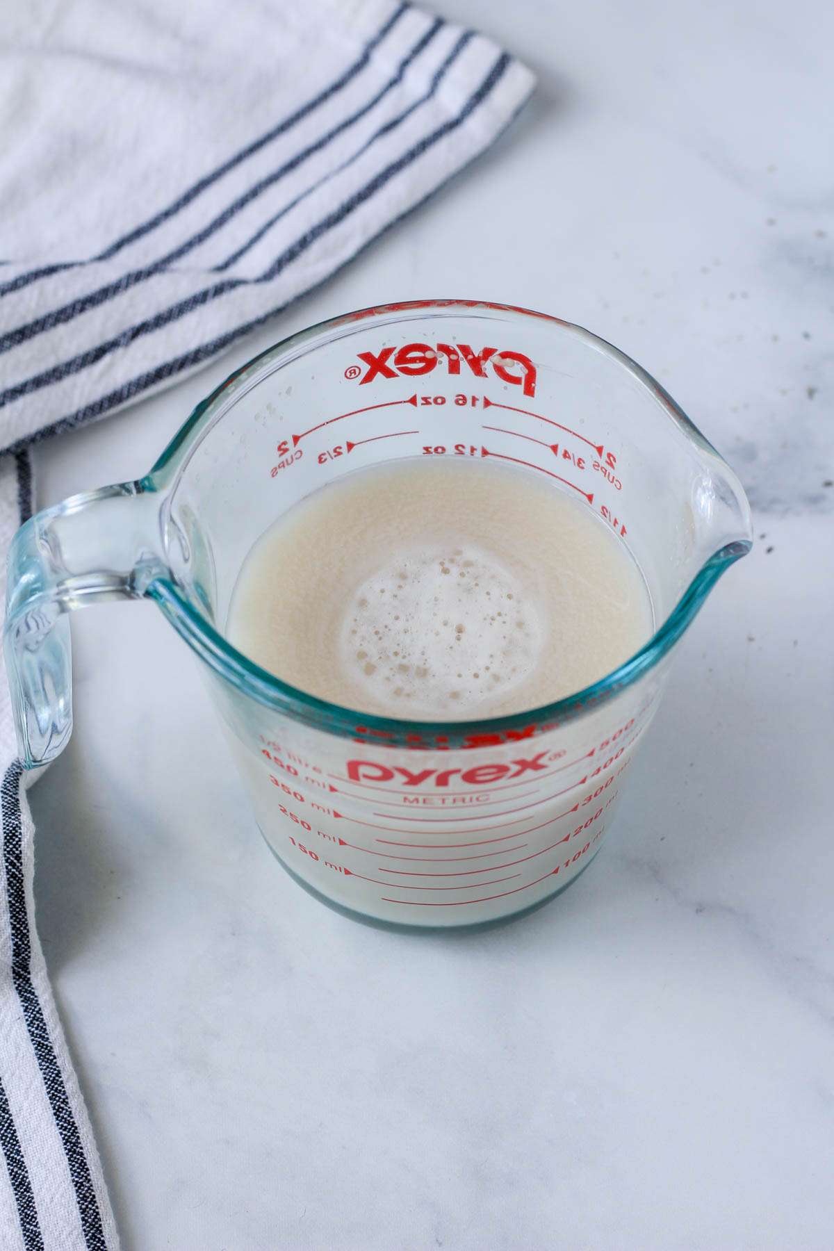 A liquid measuring cup with warm water and yeast.
