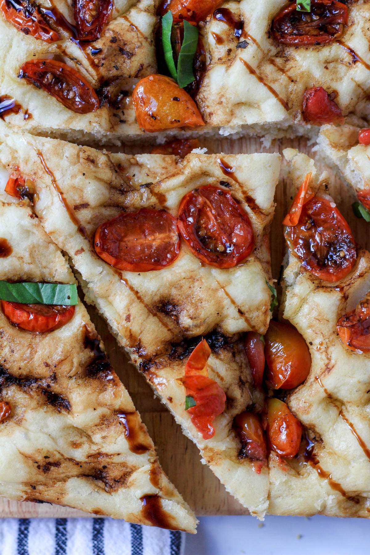 A close up of a slice of balsamic marinated tomato focaccia bread drizzled with balsamic glaze.