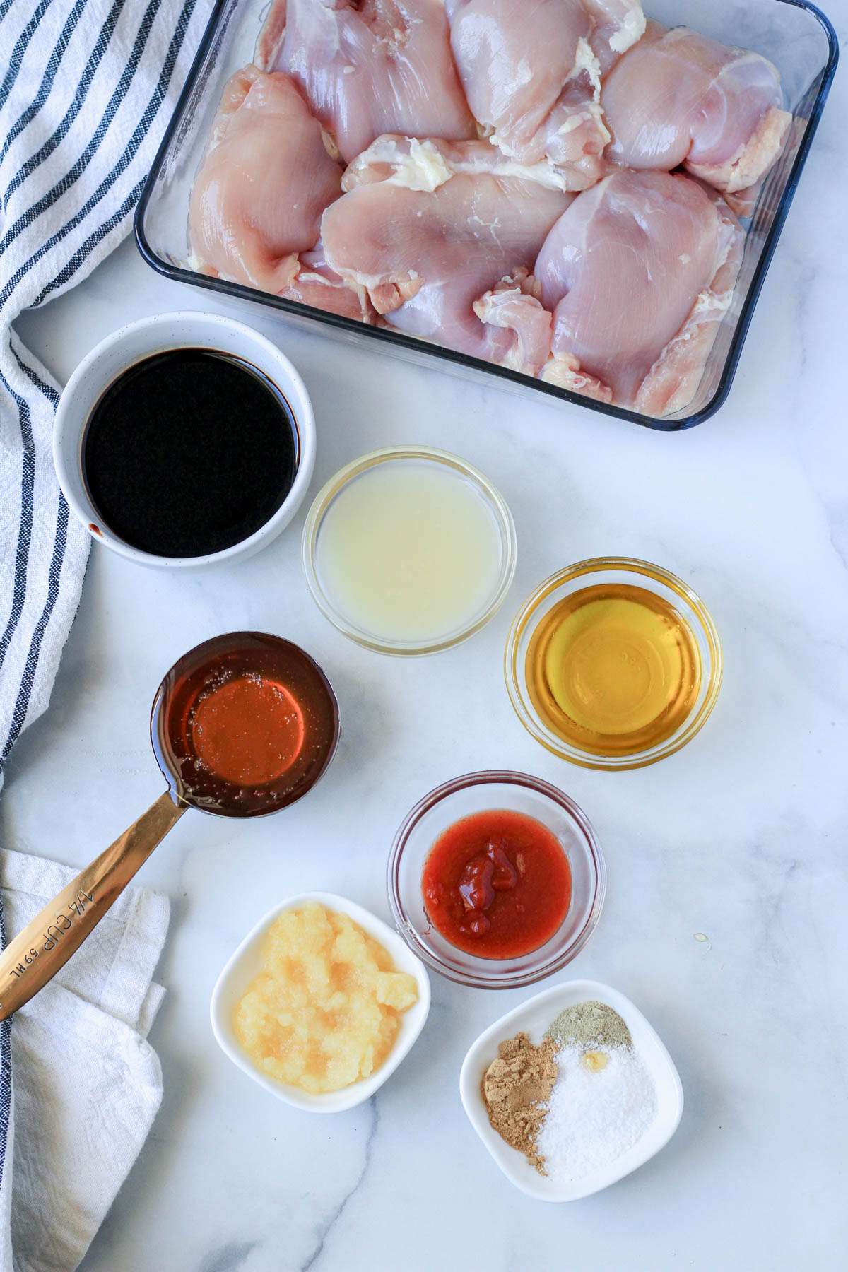Chicken thighs and the marinade ingredients on a white counter.