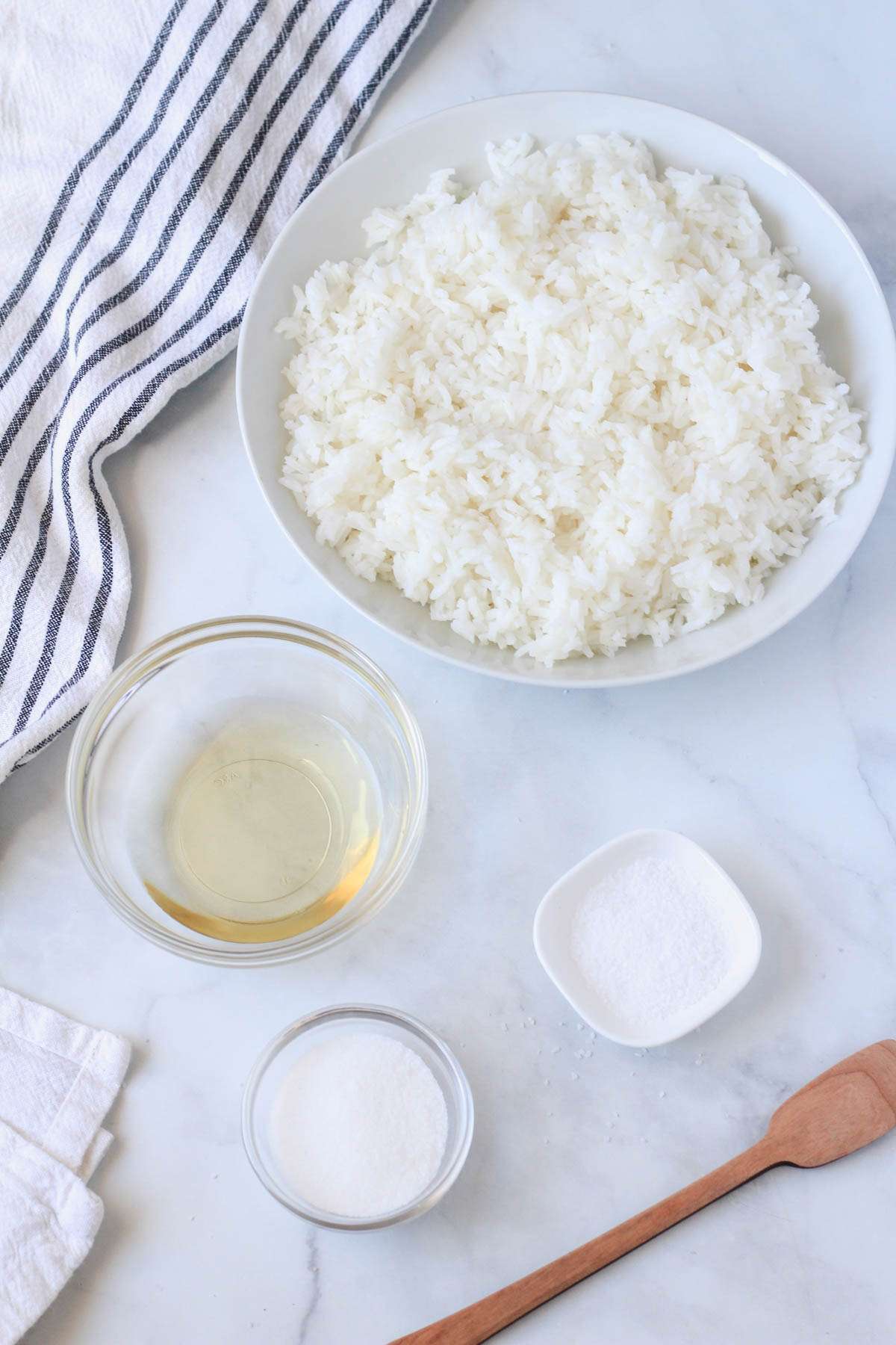 Ingredients for sticky rice on a white counter with a blue and white striped towel.