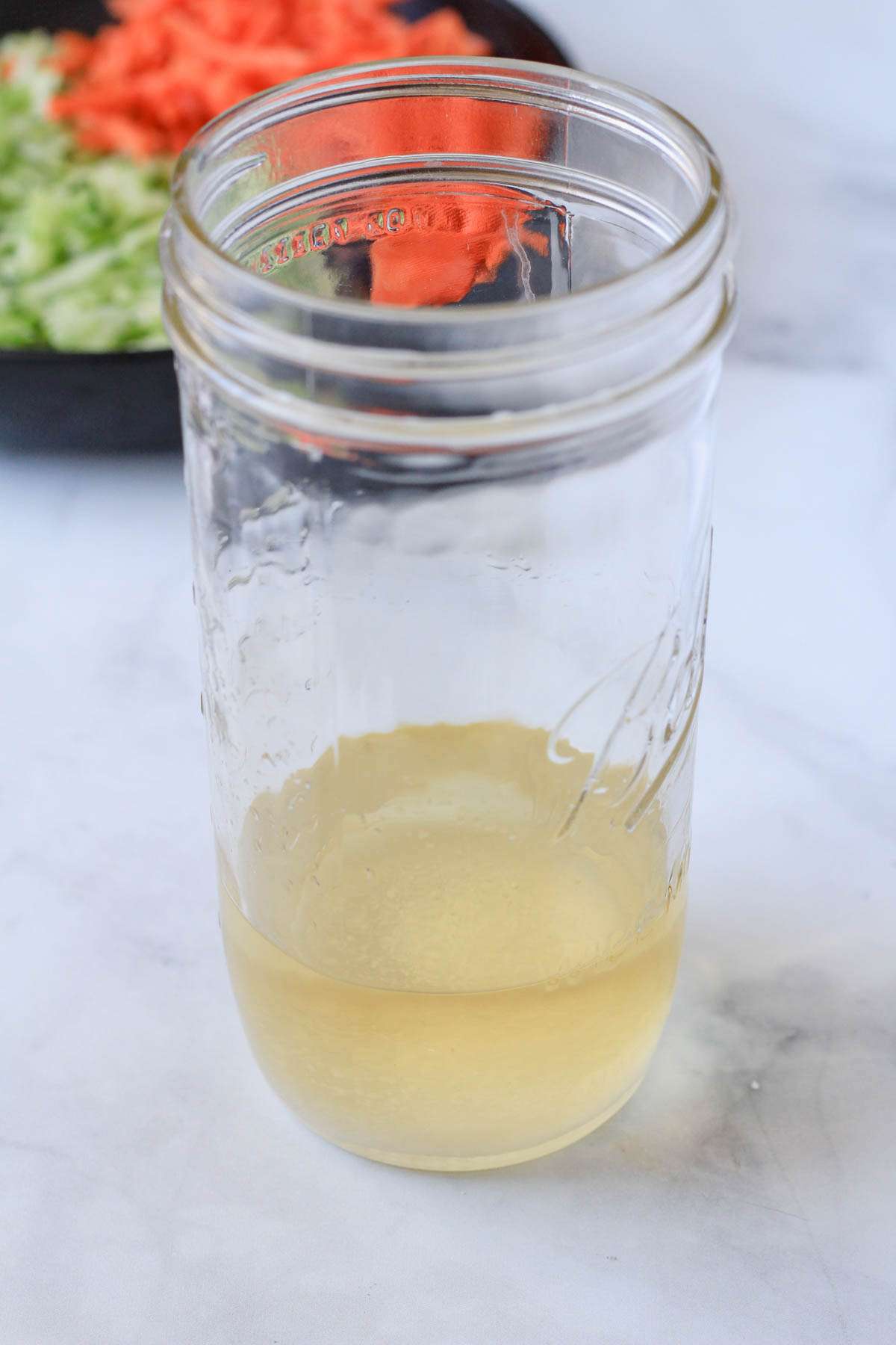 A tall mason jar with the pickling ingredients before the vegetables are added.