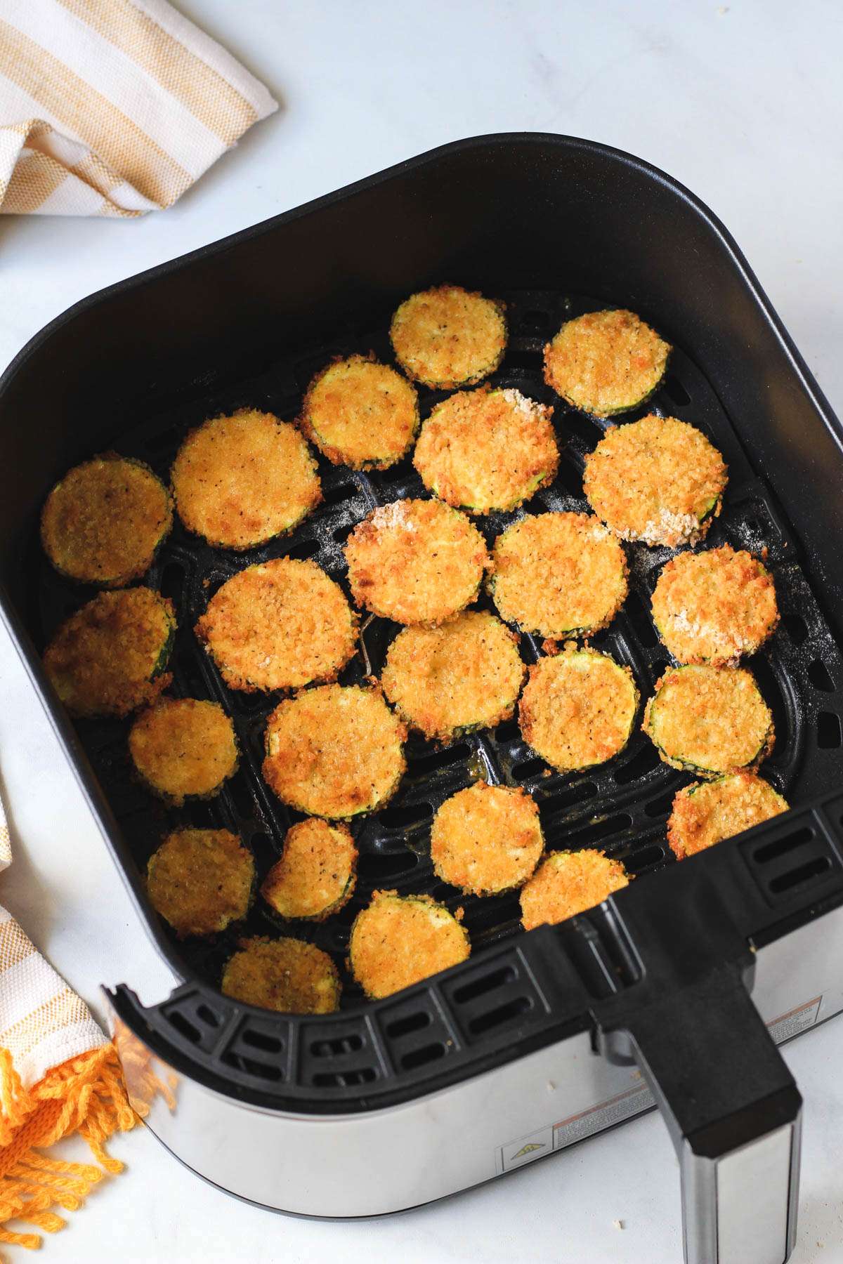 The basket of an air fryer with spicy air fryer zucchini bites after they air fry.