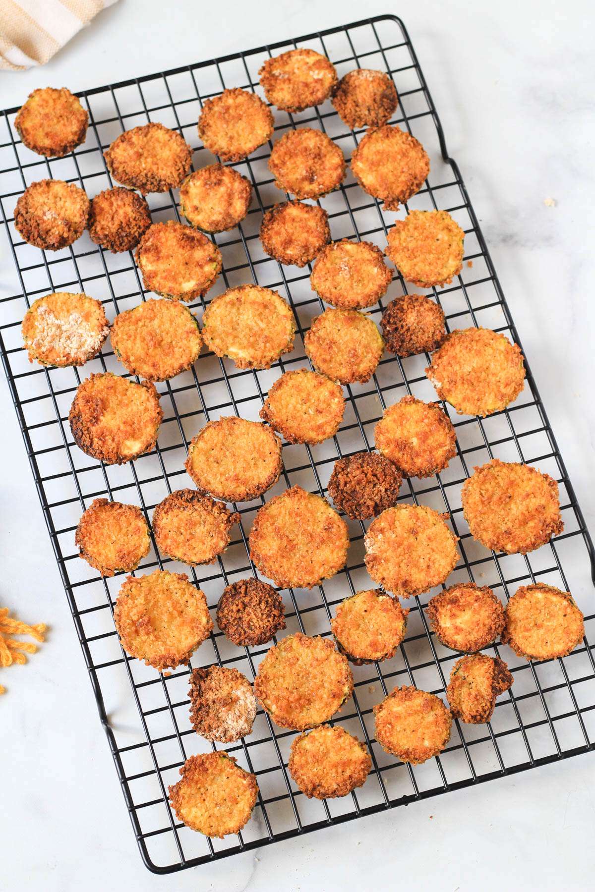 A wire cooling rack covered in air fryer spicy zucchini bites while they cool.