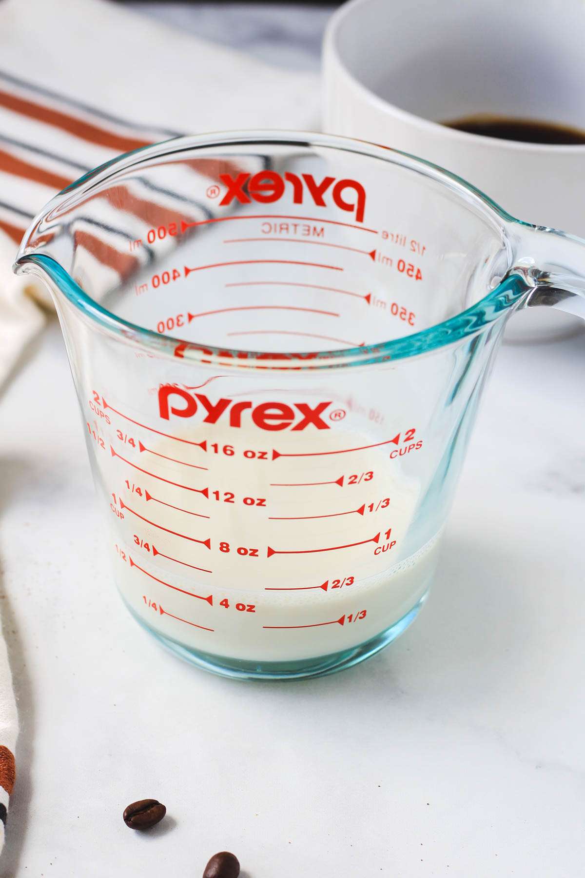 A liquid measuring cup with hot oat milk.