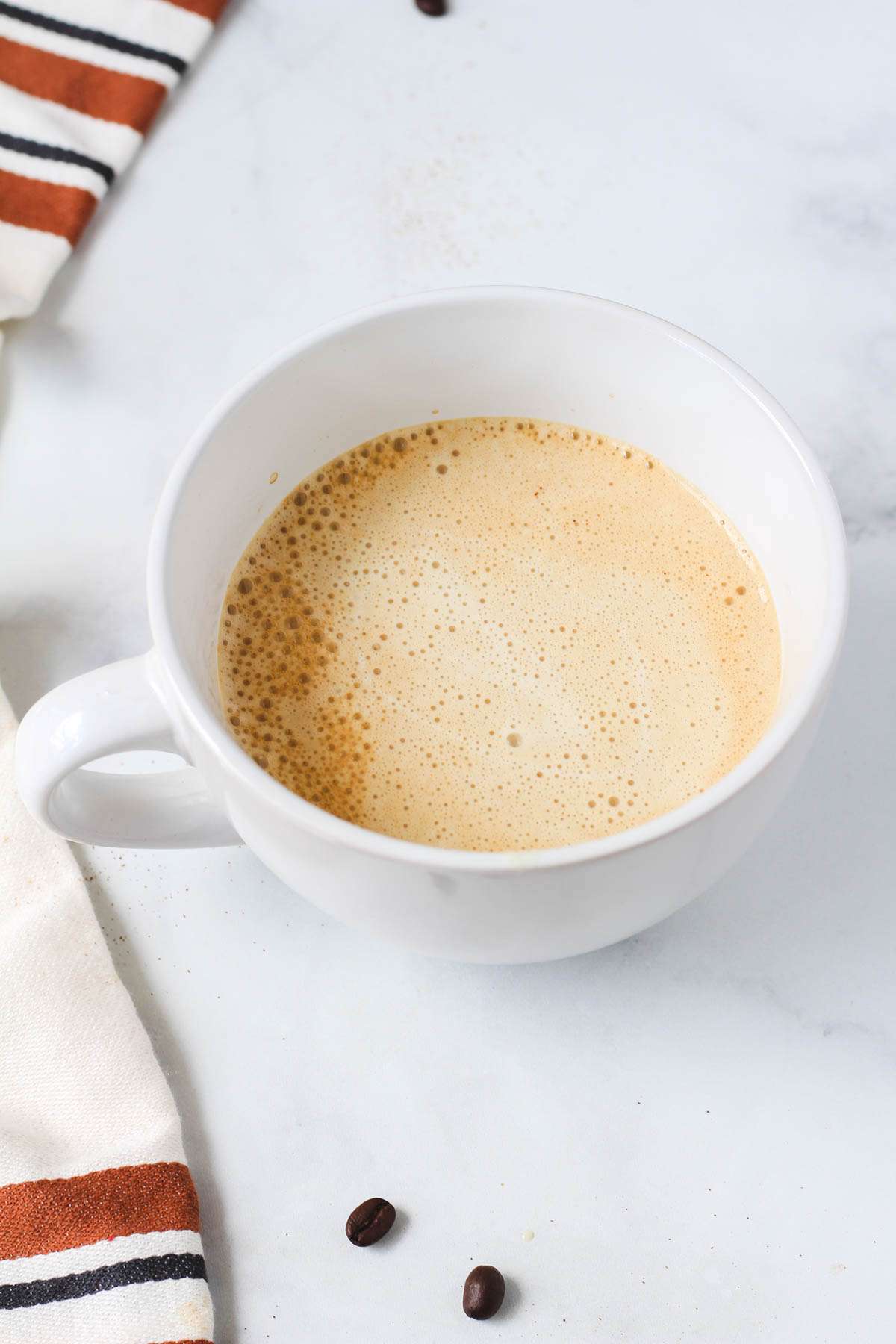 A large white cup with vanilla proffee after pouring the protein over the coffee.