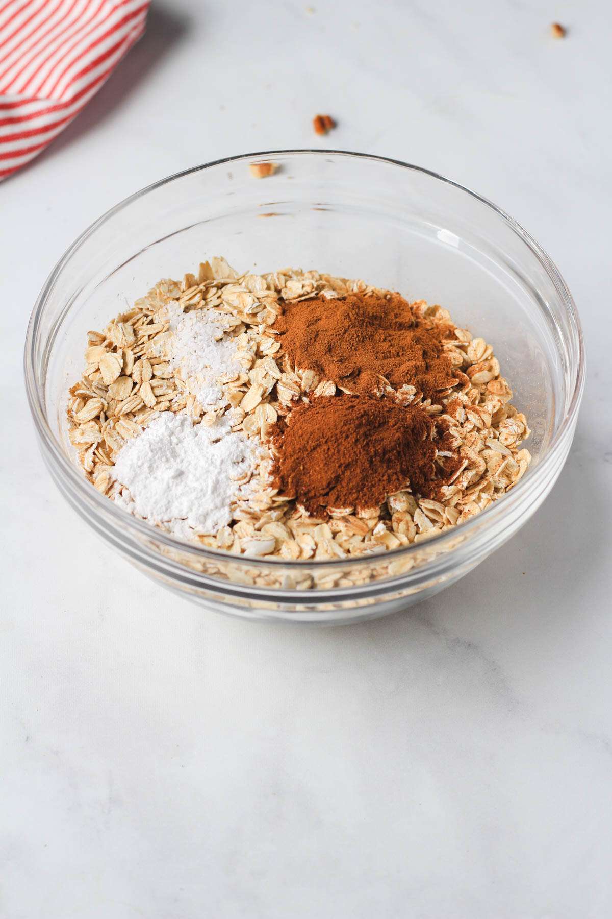 A glass bowl with the dry ingredients for apple pie baked oatmeal.