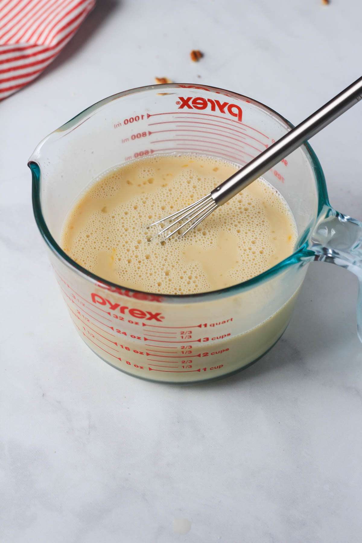 A liquid measuring cup with the wet ingredients for apple pie baked oatmeal after mixing together.