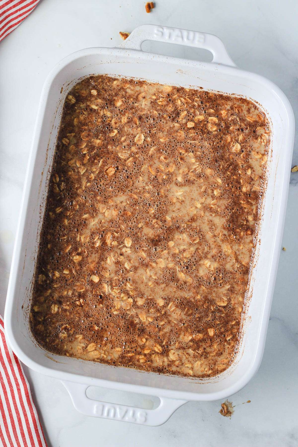 A baking dish with the wet and dry ingredients for apple pie baked oatmeal mixed together.