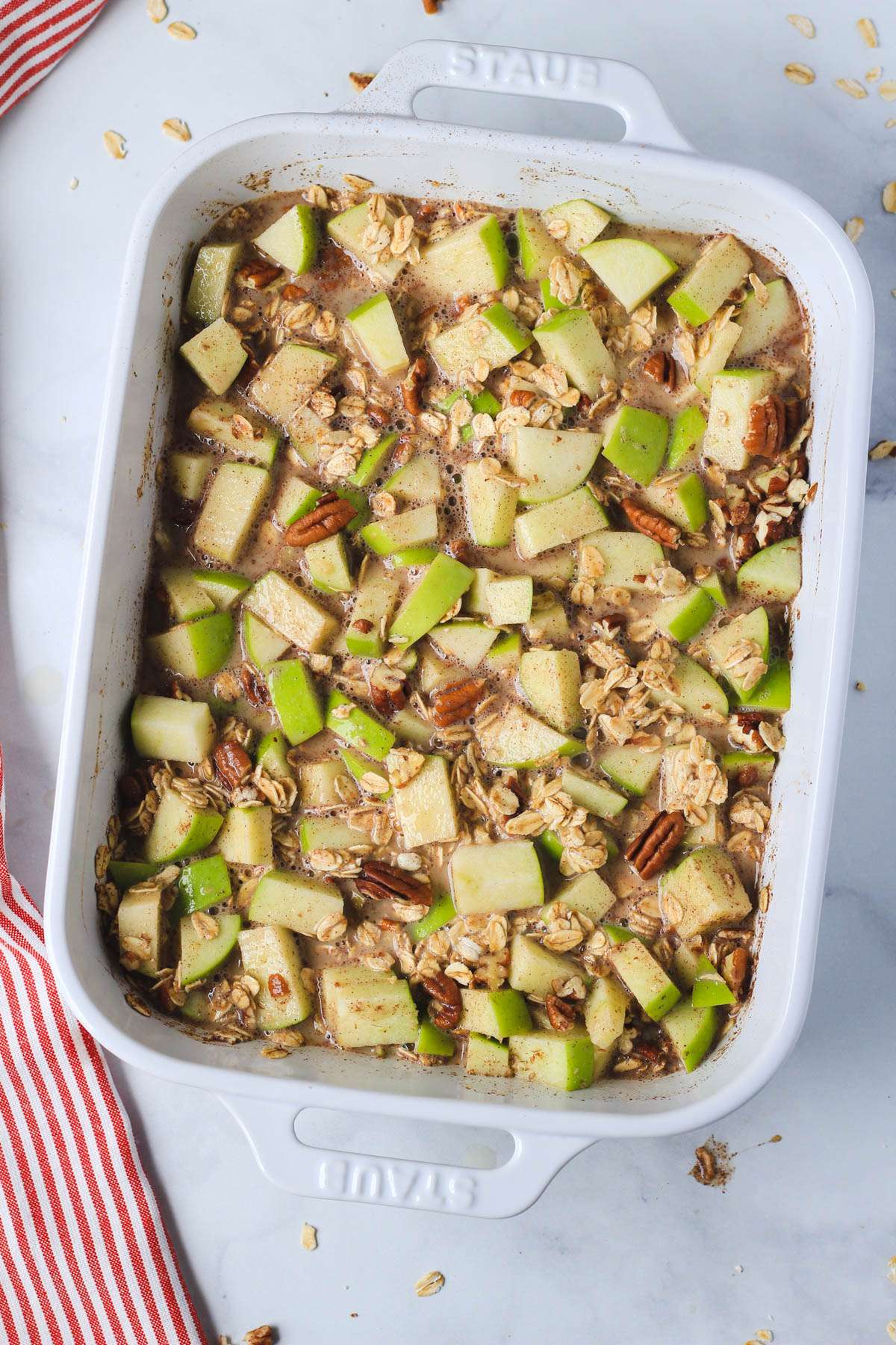 A white baking dish of apple pie baked oatmeal before baking.