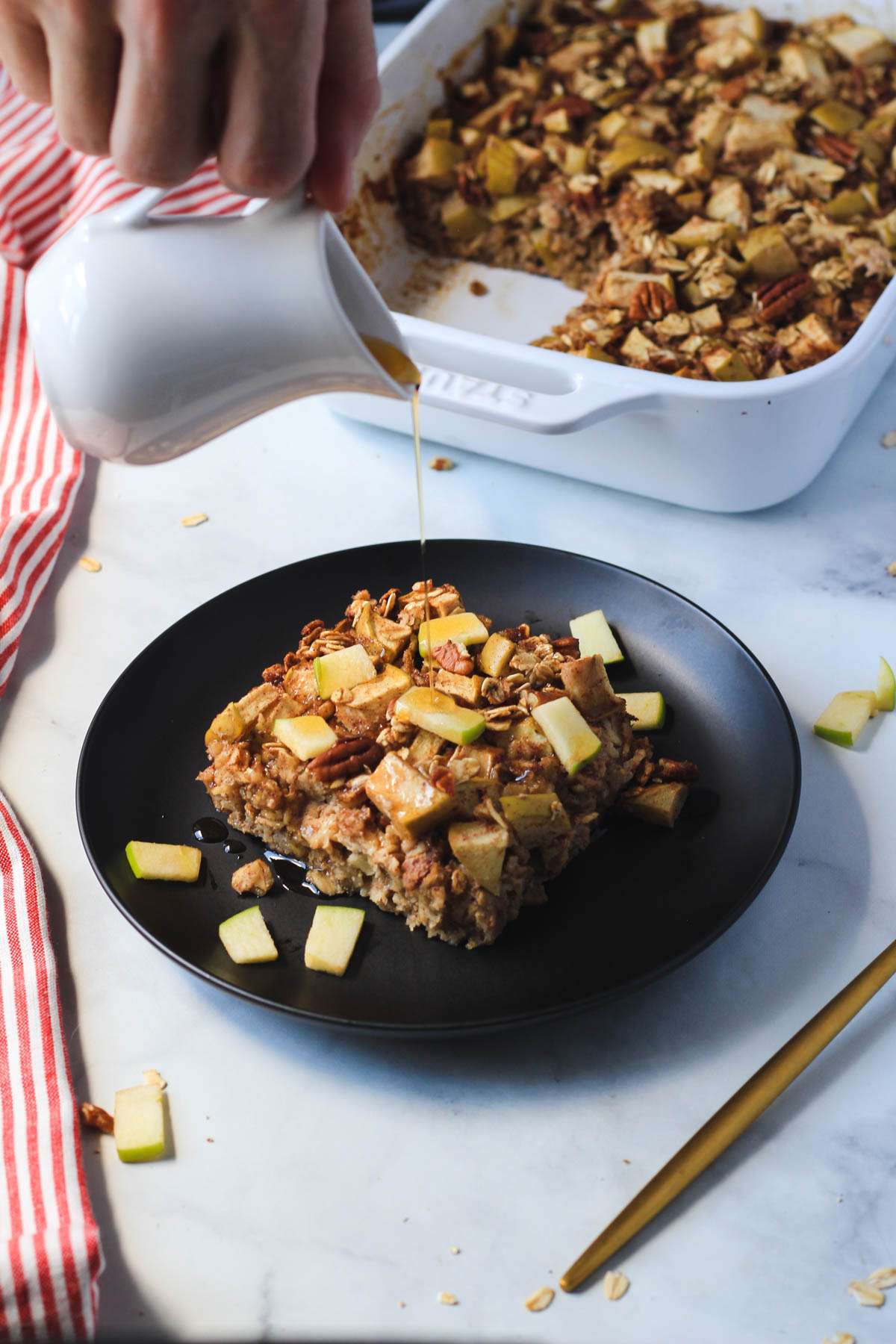 A hand pouring maple syrup over the baked oatmeal square.