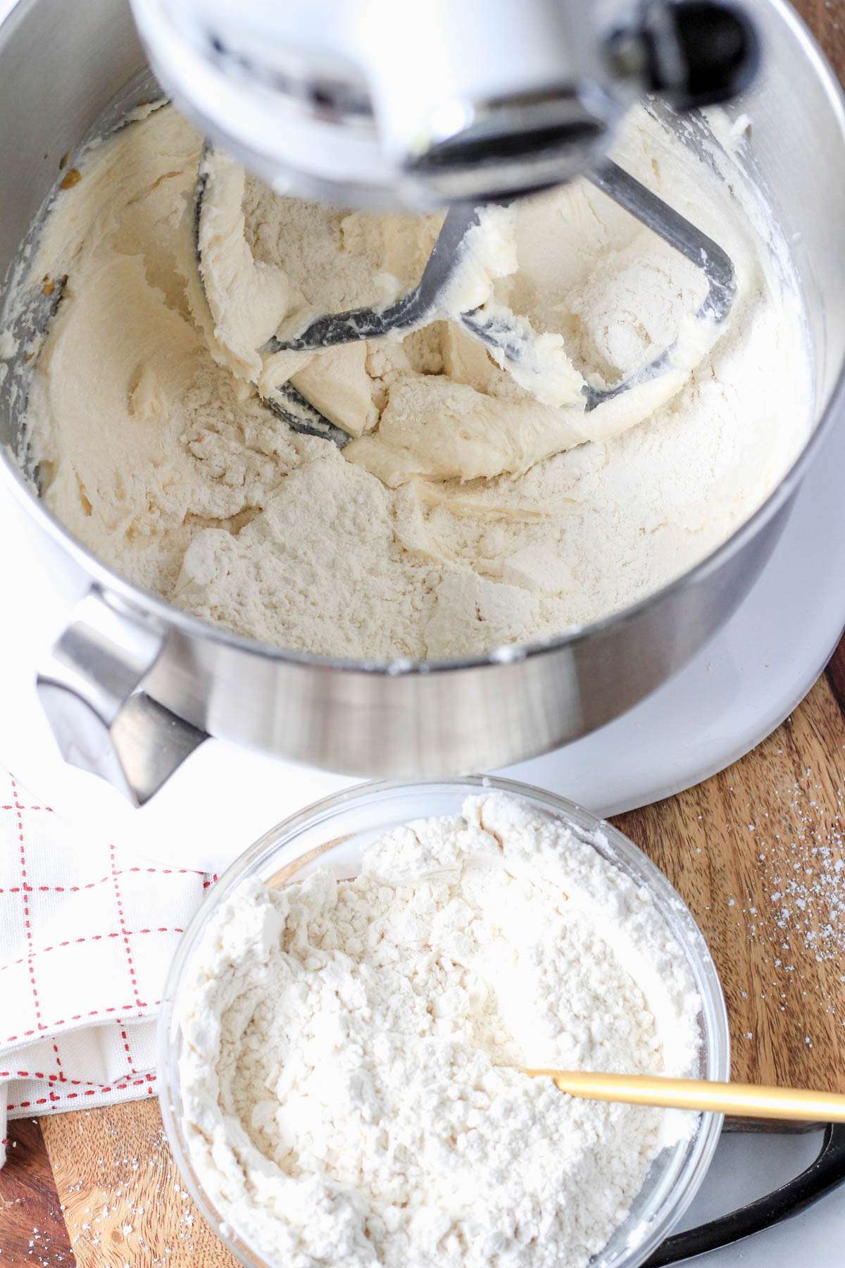 A small mixing bowl with dry ingredients in front of a silver mixing bowl with wet ingredients.