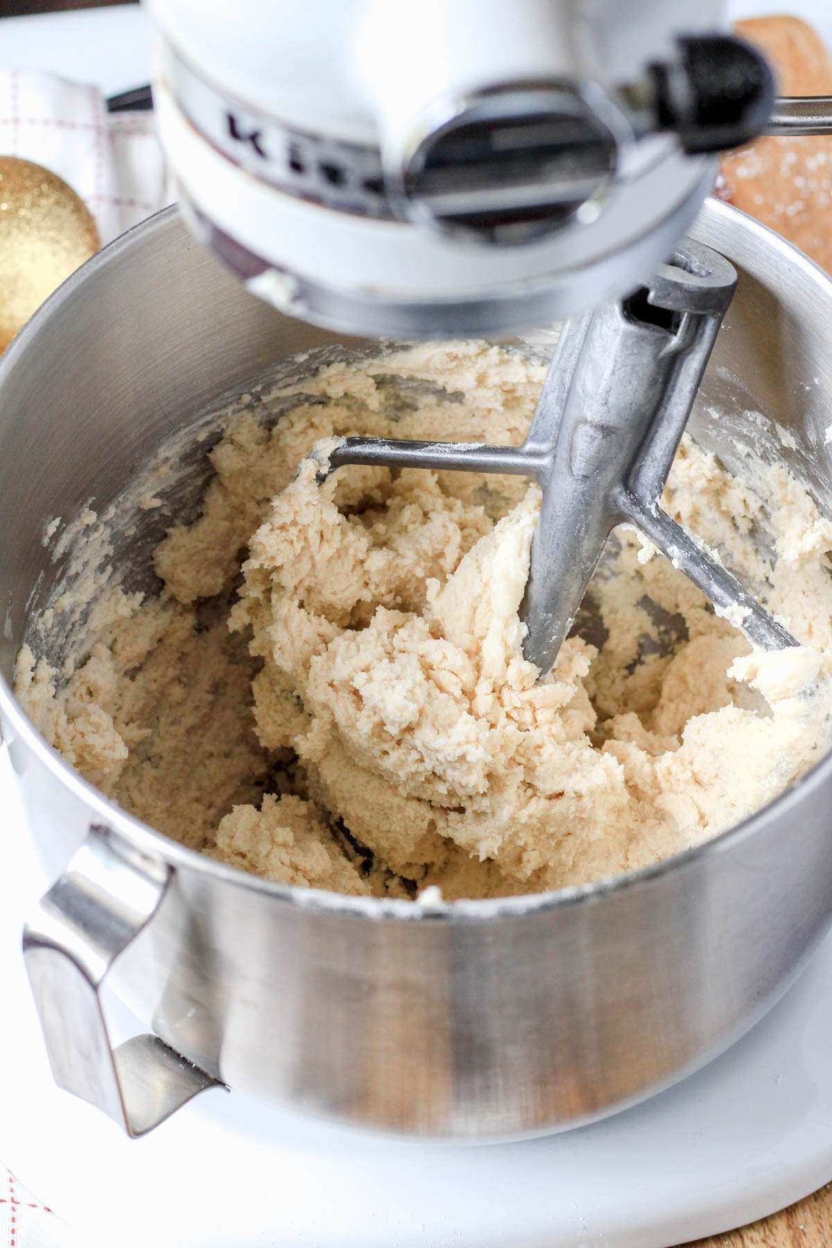 A silver mixing bowl with a paddle attachment and the vegan shortbread dough in the mixing bowl.