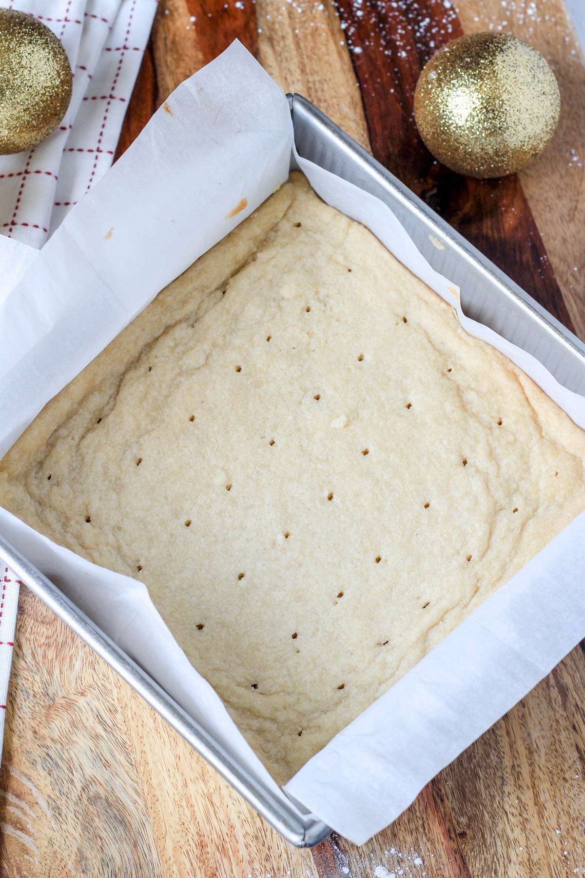 A lined baking dish on a wooden counter with classic vegan shortbread after baking.