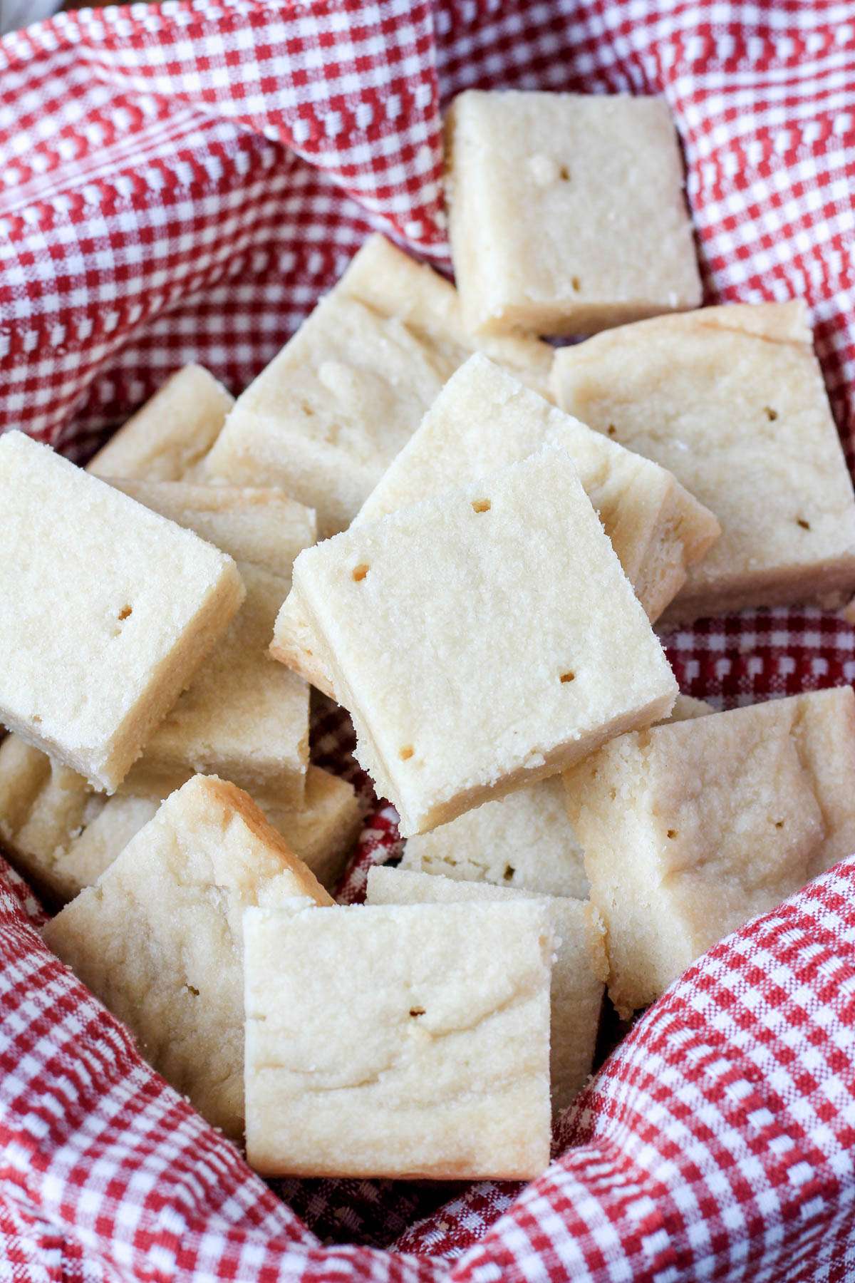 Cut squares of classic vegan shortbread cookies in a white and red towl.