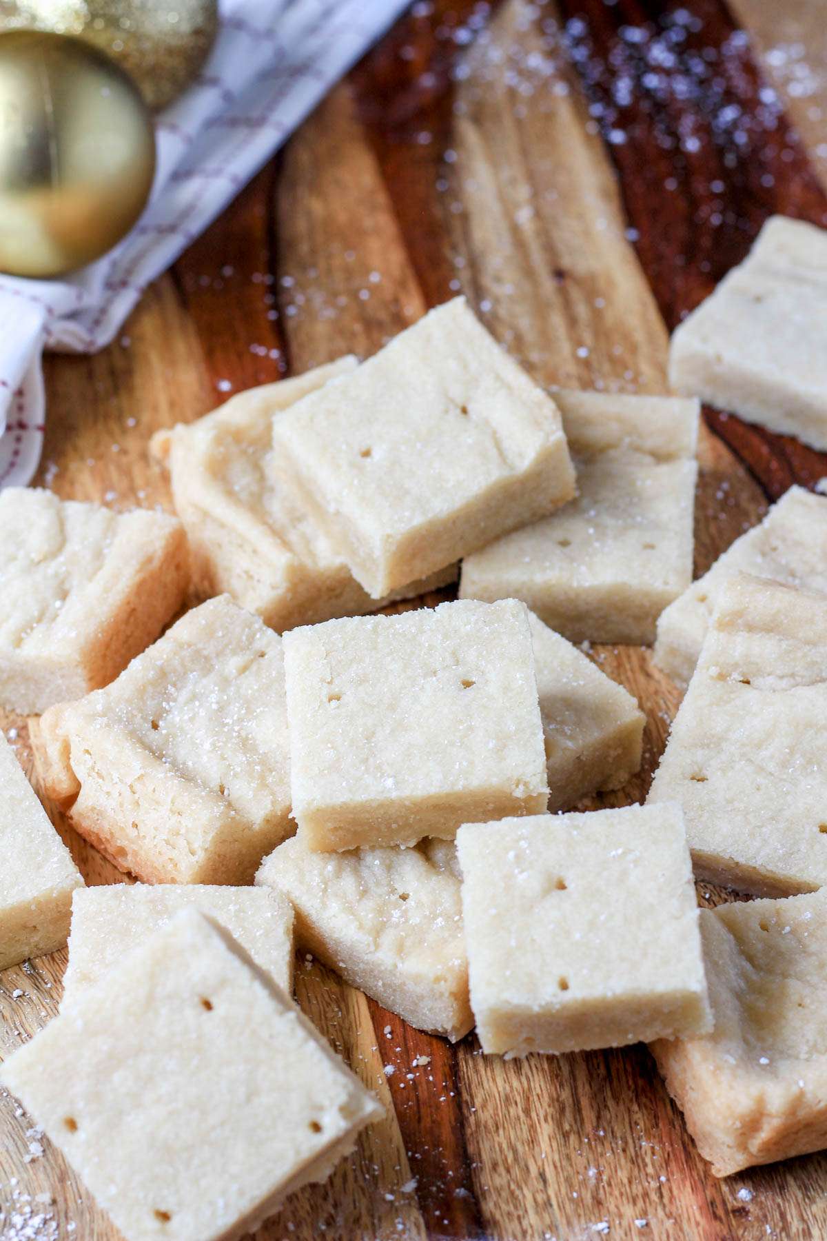 Cut pieces of vegan shortbread in a pile on a wooden counter.
