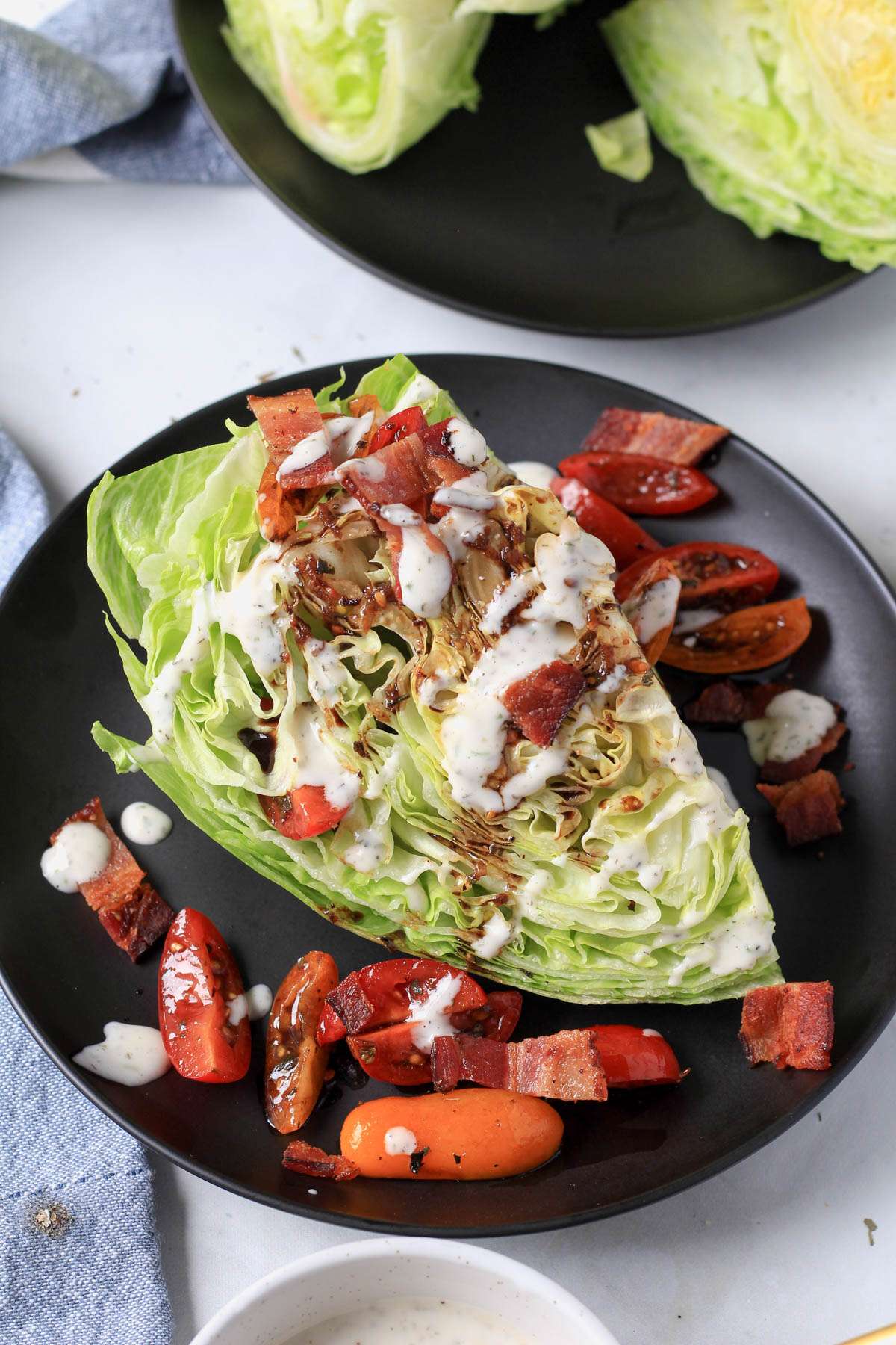 A dairy-free wedge salad topped with tomatoes, bacon, and dairy-free ranch.