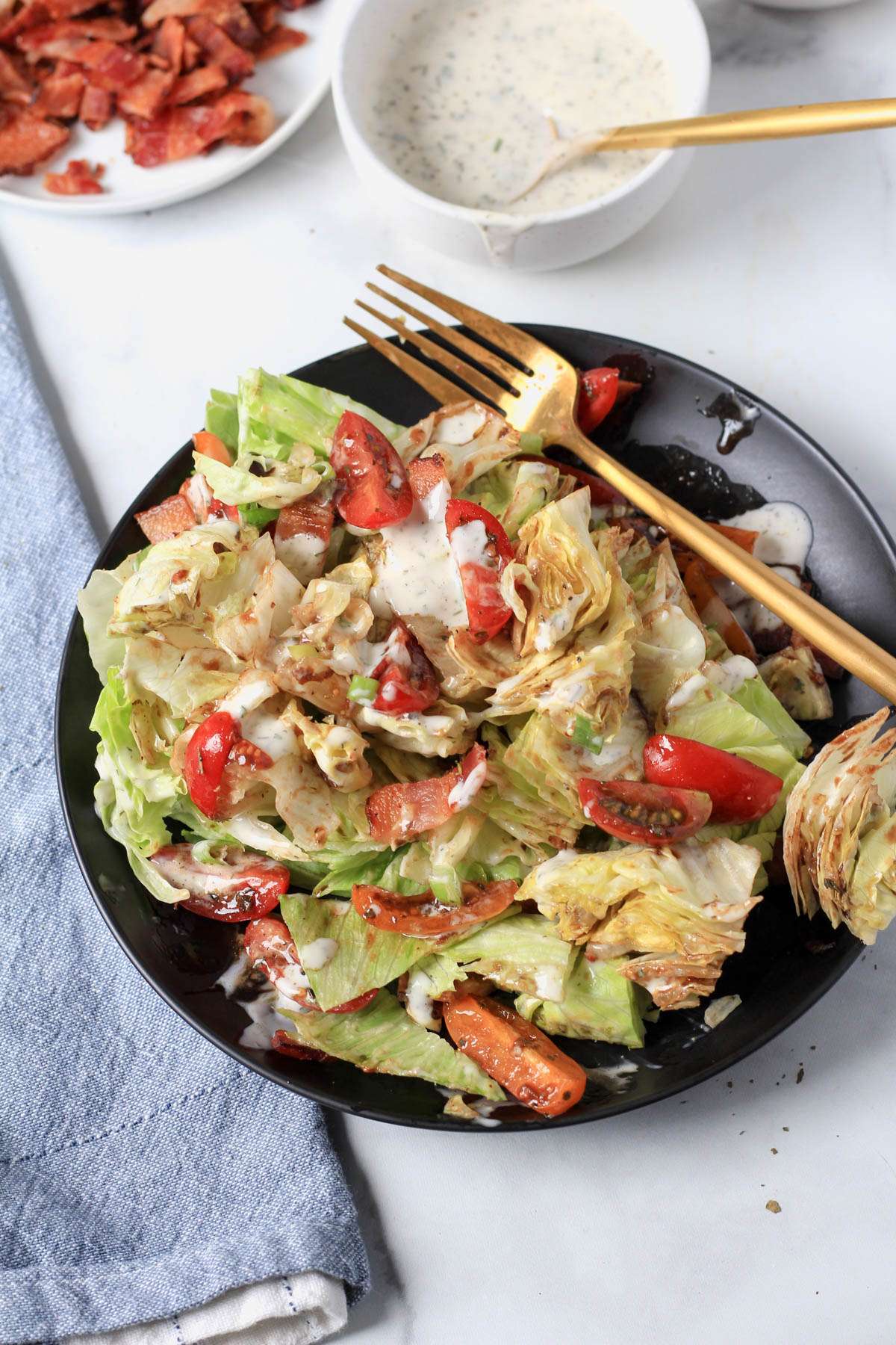 A black plate with chopped dairy-free wedge salad and a gold fork to the right.