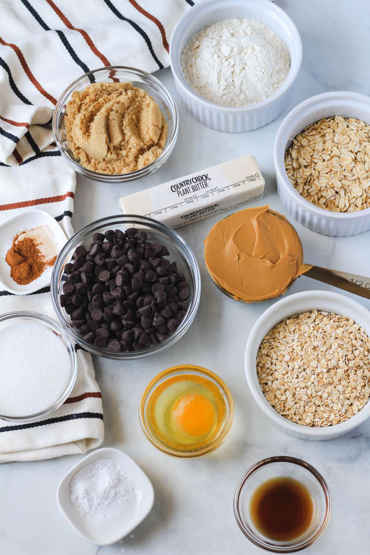 Ingredients for peanut butter oatmeal chocolate chip cookies on a white counter.