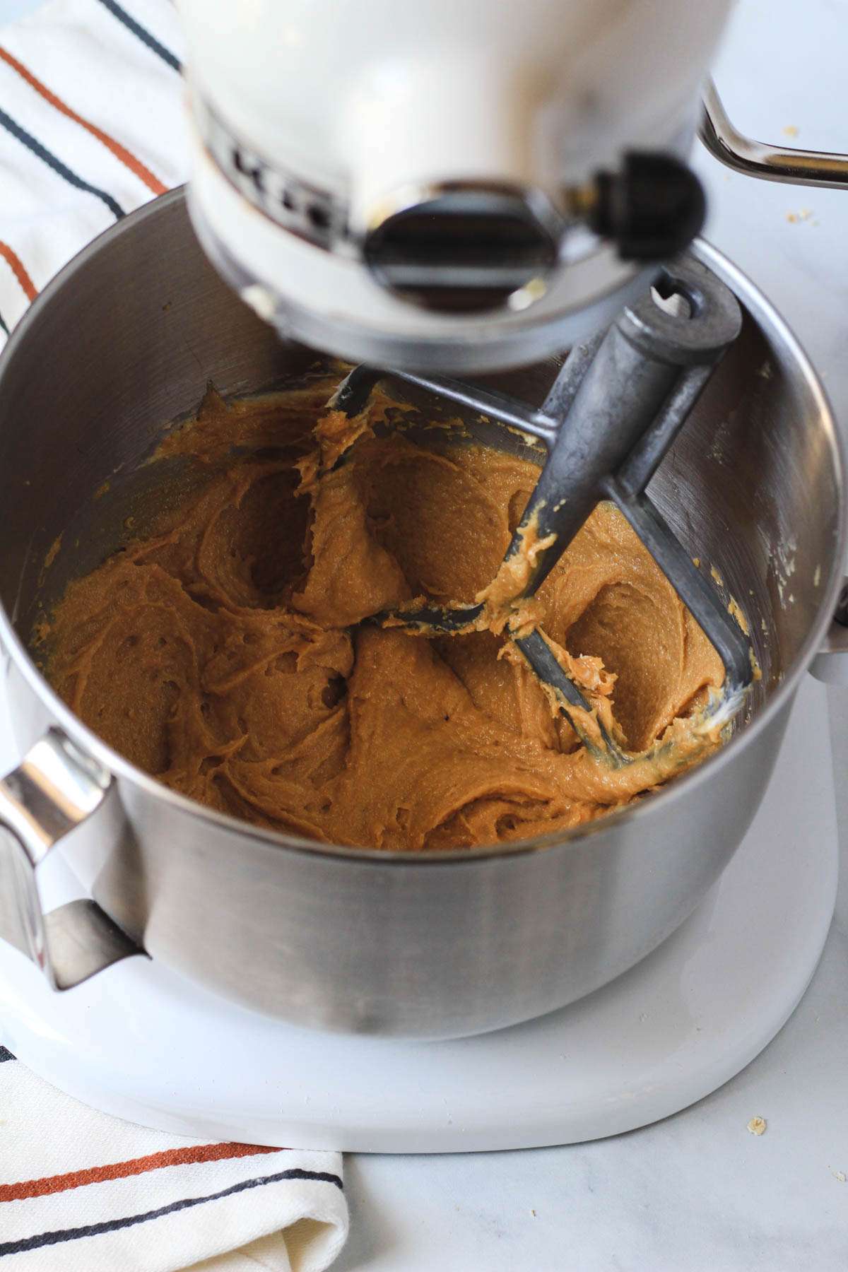 A silver mixing bowl with creamed peanut butter mixture.