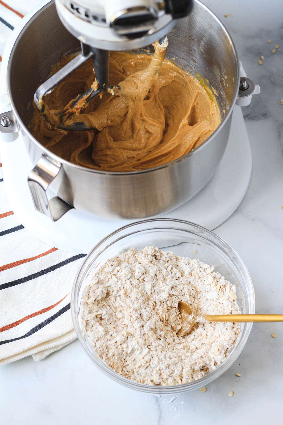 A glass mixing bowl with the dry ingredients front of a silver mixing bowl.